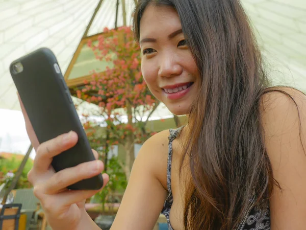 年轻美丽和快乐的亚洲韩国妇女使用互联网社交媒体应用程序在手机上微笑愉快享受轻松户外在甜咖啡店度假旅游理念 — 图库照片