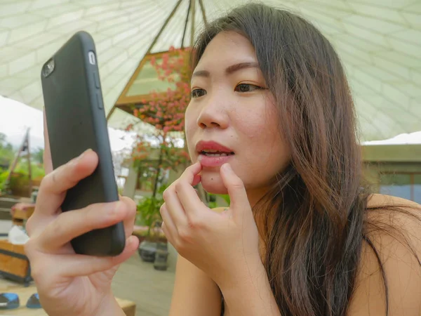 年轻美丽和快乐的亚洲韩国妇女使用手机作为镜子检查她化妆享受轻松户外在甜咖啡店度假旅游理念 — 图库照片