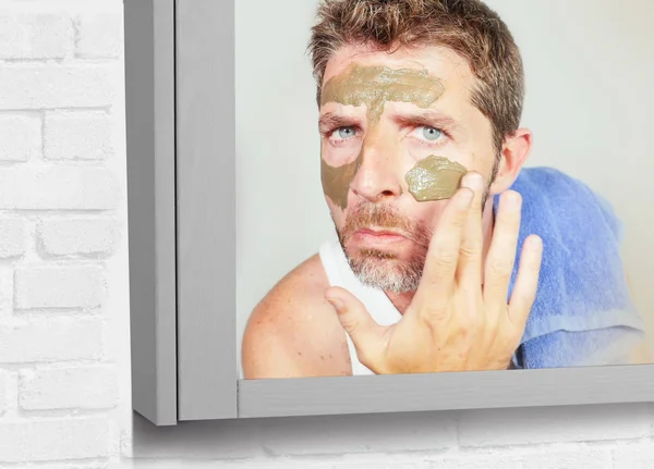 皮膚に適用する顔マスク緑クリームと浴室タオルを持つ魅力的で幸せな若者のライフ スタイル ミラー肖像画気に美しさと男性化粧品の利用の概念 — ストック写真
