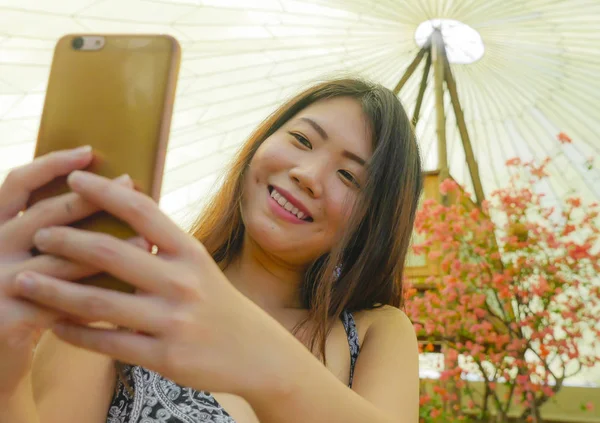 年轻漂亮和快乐的亚洲韩国旅游妇女微笑着手持手机自拍照片户外在美丽的背景下 新鲜享受假期旅行 — 图库照片
