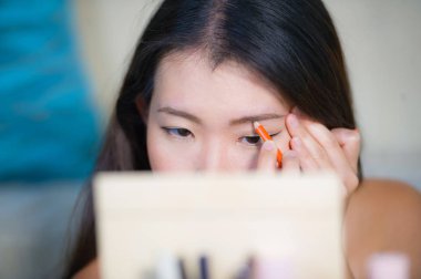 Genç güzel ve mutlu Asyalı Koreli kadın evde doğal portre yaşam tarzı yapmak kadar uzanan dışarı gitmek için hazırlanıyor aynaya bakarak kalem ile kaş profil oluşturma uygulama