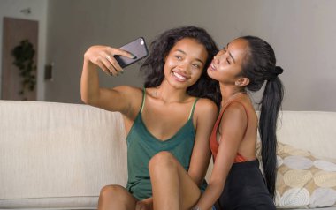 neşeli alma selfie gülümseyen genç mutlu ve güzel Asyalı kız kardeşi veya kız çift kanepe birlikte gülüyor arkadaşlık yaşam tarzı ve aşk oynak evde cep telefonu ile fotoğraf