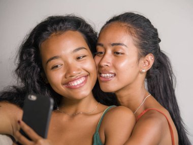 neşeli alma selfie gülümseyen genç mutlu ve güzel Asyalı kız kardeşi veya kız çift kanepe birlikte gülüyor arkadaşlık yaşam tarzı ve aşk oynak evde cep telefonu ile fotoğraf