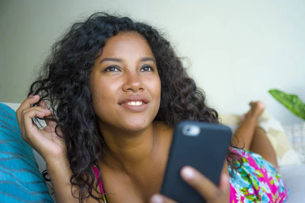 lifestyle isolated portrait of young happy and attractive latin woman at home using mobile phone networking and texting relaxed on couch smiling cheerful enjoying internet social media app