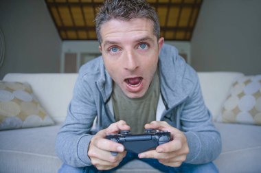 Genç yaşam tarzı portresi vurguladı ve oyun adam video oturma odası koltuk kanepe denetleyicisi tutan eğleniyor konsantre ve oyun duygu kavramı içinde vurguladı evde oyun oynarken heyecanlı