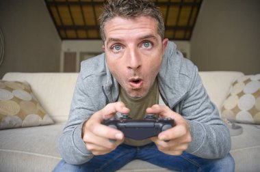 Genç yaşam tarzı portresi vurguladı ve oyun adam video oturma odası koltuk kanepe denetleyicisi tutan eğleniyor konsantre ve oyun duygu kavramı içinde vurguladı evde oyun oynarken heyecanlı