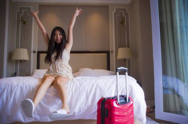 Genç mutlu ve güzel yaşam tarzı portresi Asya turizm seyahat bavul kadınla yatakta zevk oynarken beş yıldızlı bir otel odasında geldi Korece yaz tatil gezisi heyecanlı.