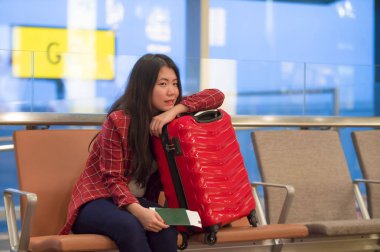 Genç güzel yaşam tarzı taze portresi ve seyahat bavul Havaalanı gidiş oturan kadınla mutlu Asyalı Koreli turist uçuş tatil gezisi neşeli gülümseyen için bekleyen gate lounge