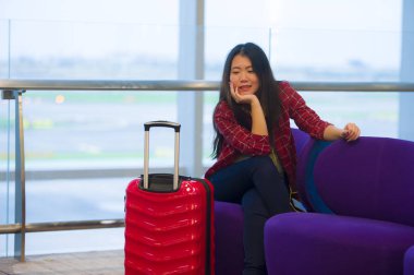 Genç güzel yaşam tarzı taze portresi ve seyahat bavul Havaalanı gidiş oturan kadınla mutlu Asyalı Koreli turist uçuş tatil gezisi neşeli gülümseyen için bekleyen gate lounge