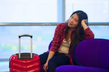 Genç güzel yaşam tarzı taze portresi ve seyahat bavul Havaalanı gidiş oturan kadınla mutlu Asyalı Koreli turist uçuş tatil gezisi neşeli gülümseyen için bekleyen gate lounge
