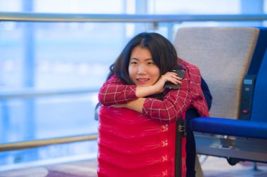 Genç güzel yaşam tarzı taze portresi ve seyahat bavul Havaalanı gidiş oturan kadınla mutlu Asyalı Koreli turist uçuş tatil gezisi neşeli gülümseyen için bekleyen gate lounge