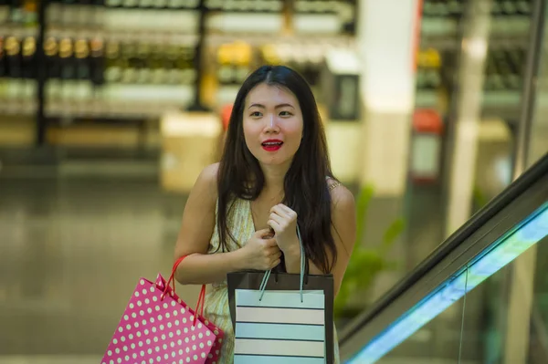 生活在室内的年轻快乐和美丽的亚洲韩国妇女的生活方式在商场自动扶梯上背着购物袋在购物中心购买欢快围绕时尚商店微笑购物狂女性概念 — 图库照片
