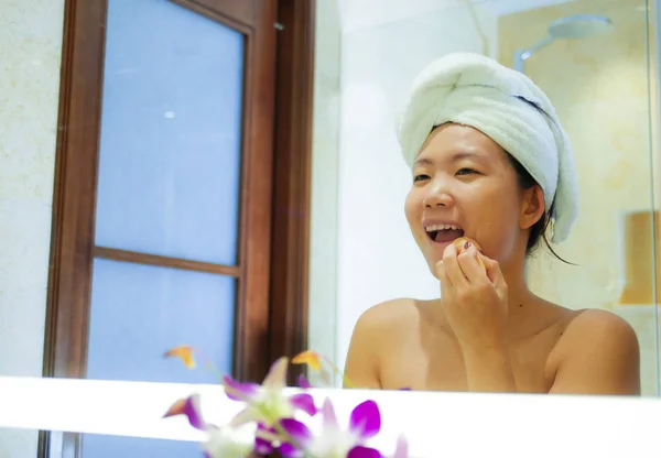 生活清新的年轻快乐和美丽的亚洲华人妇女在家里或酒店卫生间裹着浴巾应用化妆欢快和自然的女性美容和皮肤护理 — 图库照片