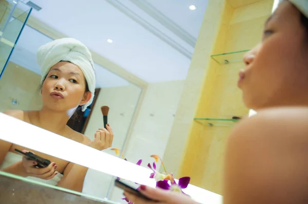 若い幸せで 美しいアジア中国の女性自宅またはホテルのバスルームは明るく自然な女性の美しさとスキンケアでメイクを適用するトイレのタオルに包まれた肖像画を新鮮なライフ スタイル — ストック写真