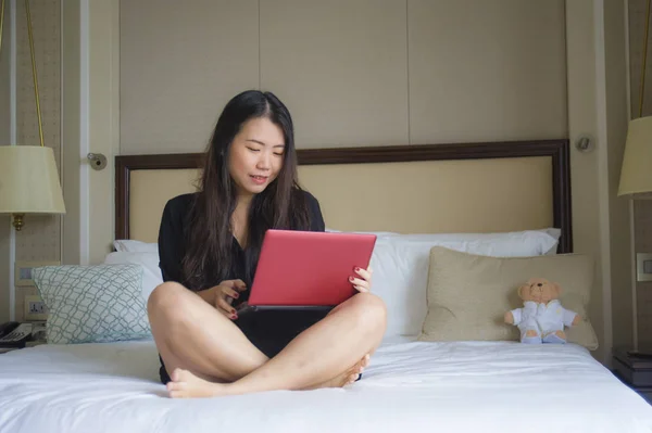 年轻快乐和放松的生活方式肖像在酒店客房床上的亚洲韩国妇女工作与笔记本电脑愉快的商务旅行和成功的企业家概念 — 图库照片