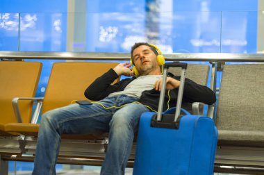yaşam tarzı portre havaalanında bavul yatılı kapısında uçuşu için bekleyen kulaklık ile müzik dinlemek adamla genç çekici ve yorgun turizm seyahat ve tatil concep tatil