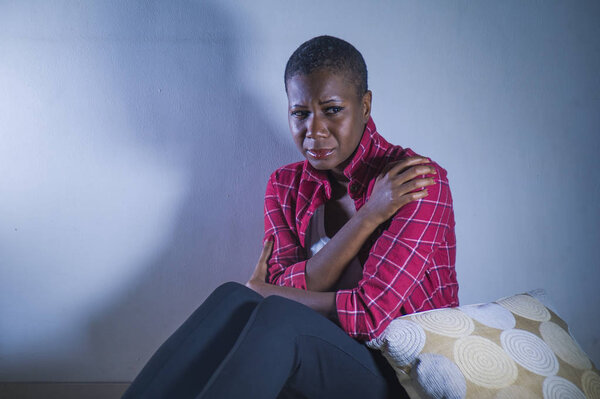 lifestyle indoors shady portrait of young sad and depressed black african American woman sitting at home floor feeling desperate and worried suffering pain and depression in dramatic light