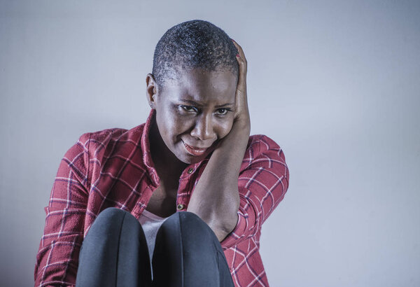 lifestyle indoors shady portrait of young sad and depressed black african American woman sitting at home floor feeling desperate and worried suffering pain and depression in dramatic light