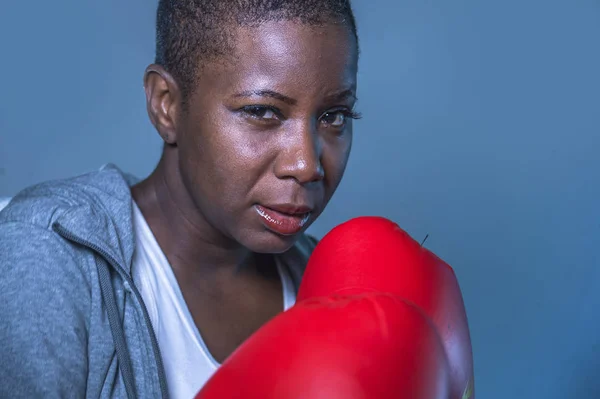 close up face portrait of young angry and defiant black african American sport woman in boxing gloves training and posing as a dangerous fighter in fitness gym and fight workout concept