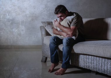 düşünceli ve dalgın sorun holding yastık acı ağrı ve depresyon hissi gölgeli evde koltukta oturan üzgün ve depresyonda gencin dramatik ışık portre yaşam tarzı kaybetti