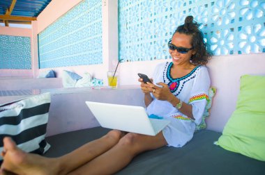 online dizüstü bilgisayar ve cep telefonu başarılı girişimci ve dijital göçebe yaşam tarzı ile çalışan kadın arayan genç çekici ve mutlu hipster açık havada portresi