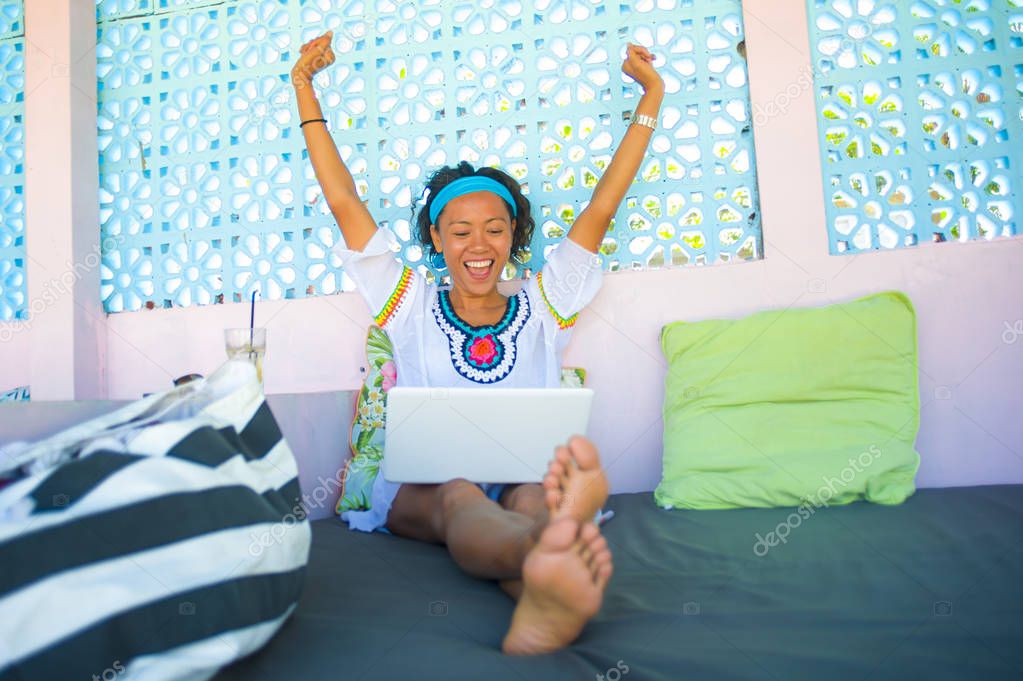 outdoors portrait of young attractive and happy hipster looking woman working online with laptop computer at cool cafe gesturing excited victory and success in digital nomad traveler lifestyle