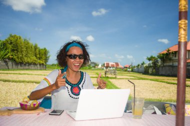 yaşam tarzı açık havada dizüstü bilgisayar ve cep telefonu üzerinden dijital göçebe iş kavramı güzel kafede çalışan genç mutlu ve çekici afro Amerikan karma etnik köken kadın portresi 