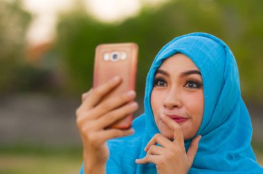 Genç mutlu portre yaşam tarzı ve güzel turistik kadın Müslüman türban başörtüsü cep telefonu yalnız tatil seyahat ve smartphone teknoloji kavramı içinde poz ile selfie fotoğraf çekimi