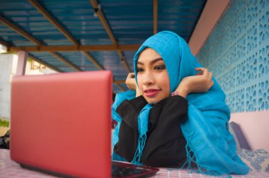 yaşam tarzı açık havada dikey genç güzel ve mutlu kadın Müslüman Tesettür baş eşarp rahatlatıcı kahve dükkanında Internet kullanarak ağ dizüstü bilgisayar ya da sahip eğlenceli ile çalışma 