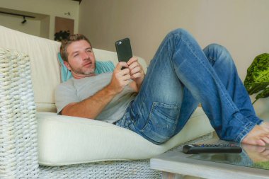 yaşam tarzı kapalı portre genç yakışıklı ve çekici mutlu adamın cep telefonu online app dating veya evde kanepe koltuk yalan smartphone ile ağ internet kullanımı rahat