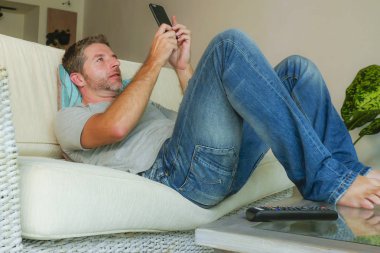 yaşam tarzı kapalı portre genç yakışıklı ve çekici mutlu adamın cep telefonu online app dating veya evde kanepe koltuk yalan smartphone ile ağ internet kullanımı rahat