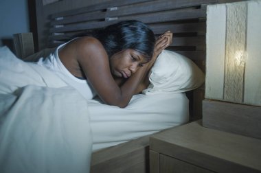 baş ağrısı ve depresyon ya da sorun uyku uykusuzluk yaşam tarzı gece portre genç üzgün ve endişeli siyah Afrikalı-Amerikalı kadın yatakta evde uykusuz ve stresli depresif duygu acı