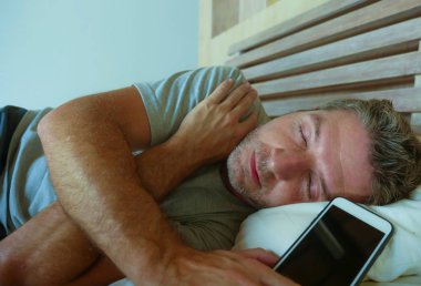 yaşam tarzı kapalı portre Genç İnternet bağımlısı yatak holding cep telefonu akıllı telefon ve sosyal medya kullanımı ve online bağımlılığı ve obsesyon kavramı elinde Uyuyan adam