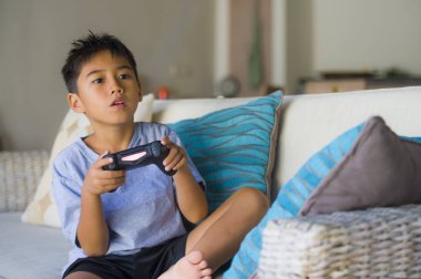 Eğleniyor zevk Latin Genç çocuk 8 yaşında heyecanlı ve mutlu oyun video oyunu online holding uzaktan kumanda portresi yaşam tarzı internet oyun çocuk bağımlılığı koltukta oturan