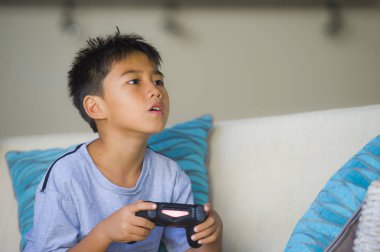 Çocuk oyun duygu ve bağımlılığı kanepede eğleniyor zevk Latin Genç çocuk 8 yaşında heyecanlı ve mutlu oyun video oyunu online holding uzaktan kumanda yaşam tarzı portresi