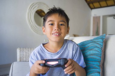 Çocuk oyun duygu ve bağımlılığı kanepede eğleniyor zevk Latin Genç çocuk 8 yaşında heyecanlı ve mutlu oyun video oyunu online holding uzaktan kumanda yaşam tarzı portresi