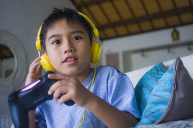 Genç Latin küçük çocuk portresi yaşam tarzı heyecanlı ve mutlu oyun video oyun online ile eğleniyor denetleyicisi tutan kulaklık oyun duygu kanepede oturup oyun bağımlılığı evlat