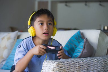 Genç Latin küçük çocuk portresi yaşam tarzı heyecanlı ve mutlu oyun video oyun online ile eğleniyor denetleyicisi tutan kulaklık oyun duygu kanepede oturup oyun bağımlılığı evlat