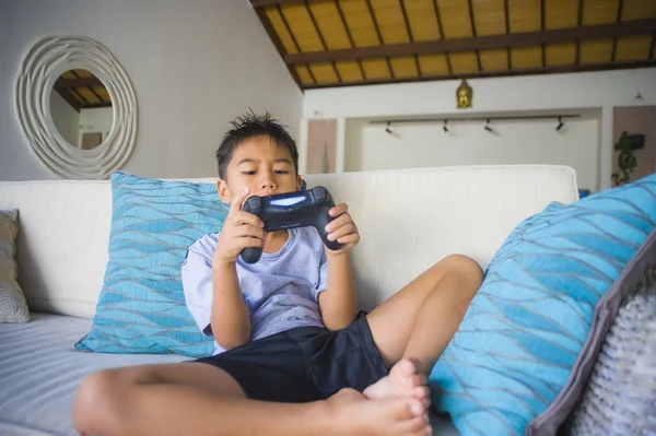 Çocuk oyun duygu ve bağımlılığı kanepede eğleniyor zevk Latin Genç çocuk 8 yaşında heyecanlı ve mutlu oyun video oyunu online holding uzaktan kumanda yaşam tarzı portresi