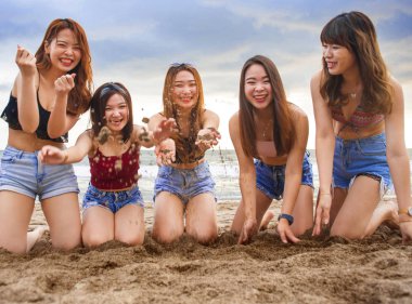 mutlu ve neşeli grup Asya Korece ve Çince genç kadını, kum birlikte kız tatil gezi ve dostluk kavramı plajda diz çökmüş ile oynayan kız portresi