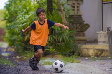 futbol açık havada çalışan ve futbol topu, eğleniyor çocuk tekmeleme Bahçe giyen eğitim yeleğe oynayan 8 veya 9 yaşında mutlu ve heyecanlı çocuk spor pratik 