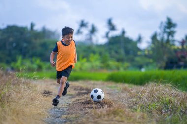 futbol açık havada çalışan ve futbol topu, eğleniyor çocuk tekmeleme Bahçe giyen eğitim yeleğe oynayan 8 veya 9 yaşında mutlu ve heyecanlı çocuk spor pratik 