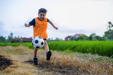 futbol açık havada çalışan ve futbol topu, eğleniyor çocuk tekmeleme Bahçe giyen eğitim yeleğe oynayan 8 veya 9 yaşında mutlu ve heyecanlı çocuk spor pratik 