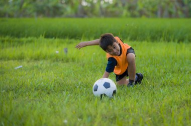 futbol açık havada çalışan ve futbol topu, eğleniyor çocuk tekmeleme Bahçe giyen eğitim yeleğe oynayan 8 veya 9 yaşında mutlu ve heyecanlı çocuk spor pratik 