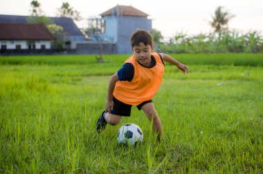 futbol açık havada çalışan ve futbol topu, eğleniyor çocuk tekmeleme Bahçe giyen eğitim yeleğe oynayan 8 veya 9 yaşında mutlu ve heyecanlı çocuk spor pratik 