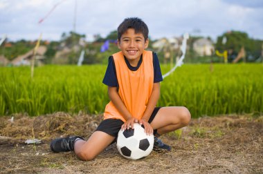 yaşam tarzı yeşil çim alan gülümseyen neşeli giyen eğitim yeleğe çocuk eğitim spor kavramı, açık havada futbol futbol topu tutan mutlu ve yakışıklı genç çocuk portresi