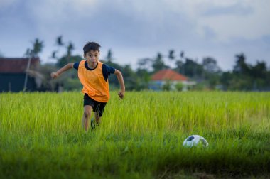futbol açık havada çalışan ve futbol topu, eğleniyor çocuk tekmeleme Bahçe giyen eğitim yeleğe oynayan 8 veya 9 yaşında mutlu ve heyecanlı çocuk spor pratik 