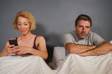 yaşam tarzı kız arkadaşı veya karısı ile sinirli sinirli kocası ya da erkek yatakta cep telefonuyla portresi, duygu adam göz ardı ve kadın internet bağımlılığı çift problem içinde üzmek