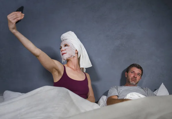 메이크업 마스크와 이상한 개념에 절망적 표정으로 침대에 Selfie 주부의 라이프 — 스톡 사진