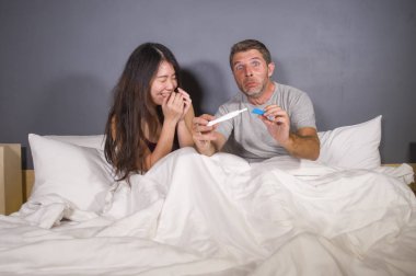 Genç güzel ve stresli çift yatakta hamilelik testi duygu mutlu ve heyecanlı ve korkmuş bir bebek bekliyor hakkında olumlu hamile sonuç tarafından arıyorsunuz